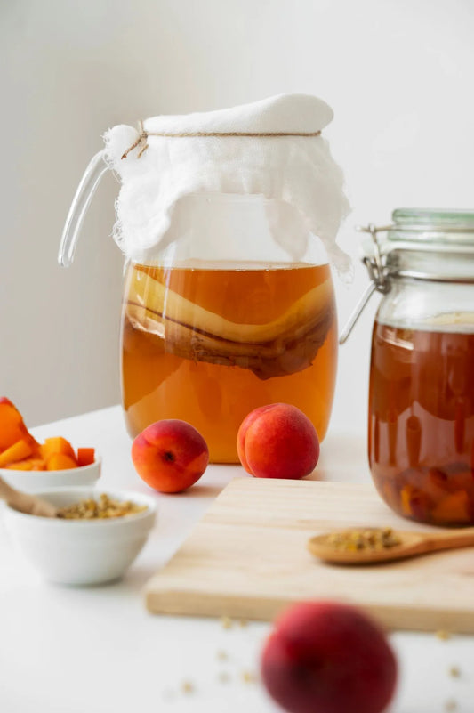 Gläser mit fermentierendem Kombucha und Scoby mit Früchten als Symbol für den Herstellungsprozess