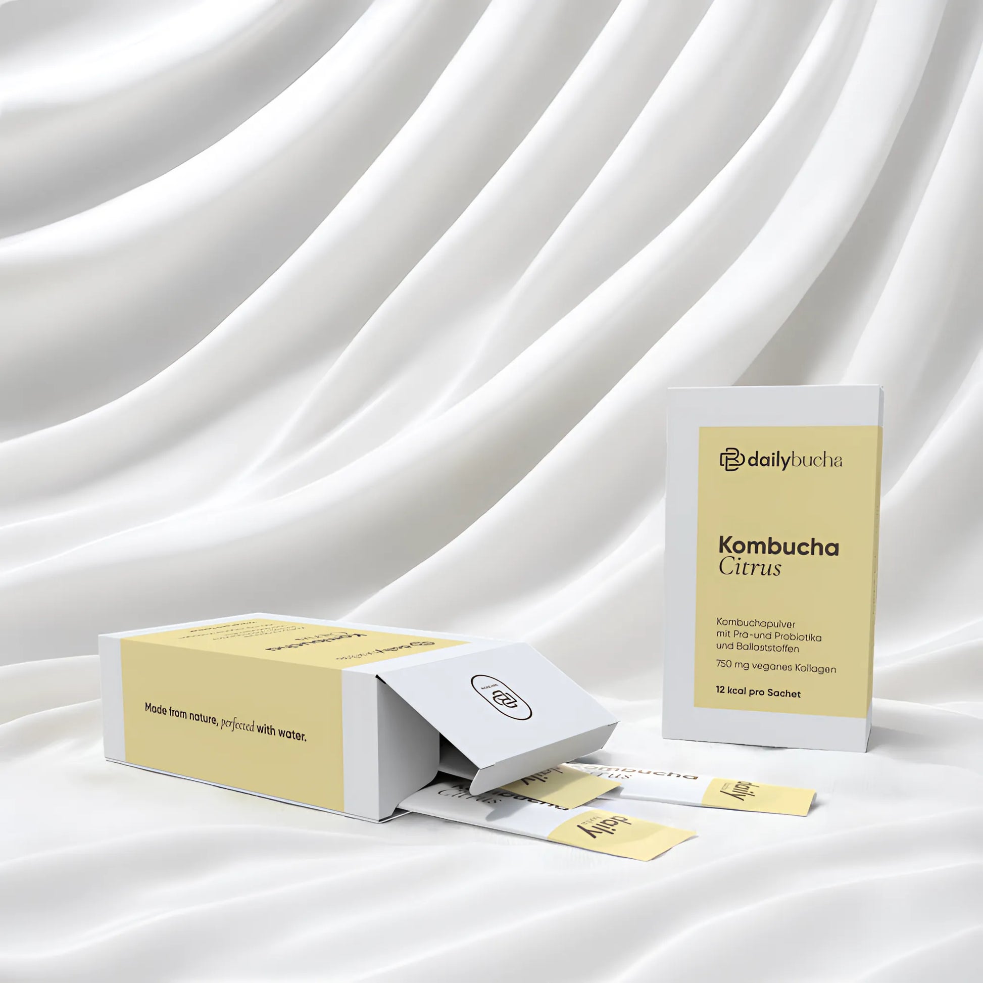 Daily Bucha Zitronen-Kombucha mit veganem Kollagen und Ballaststoffen, ohne Zuckerzusatz – geöffnete Verpackung mit Sachets und aufgestellter Box vor weißem Hintergrund